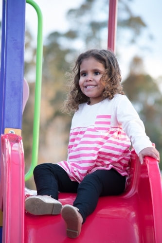 Aboriginal girl on slide at park - Australian Stock Image