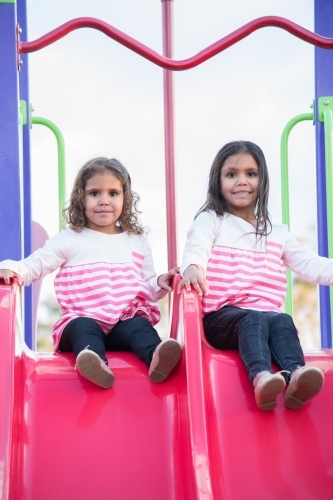 Aboriginal girls on slide at park - Australian Stock Image