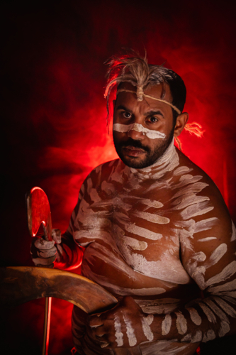 Aboriginal man holding boomerangs with red background - Australian Stock Image