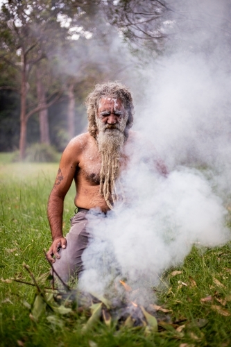 Aboriginal man kneeling in front of a fire