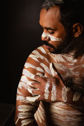 Aboriginal man painting his body with an ochre - Australian Stock Image