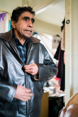 Aboriginal Man Standing while Doing Up his Jacket - Australian Stock Image