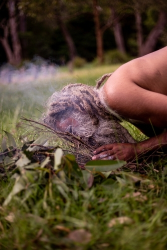 Aboriginal man starting a smoking ceremony - Australian Stock Image