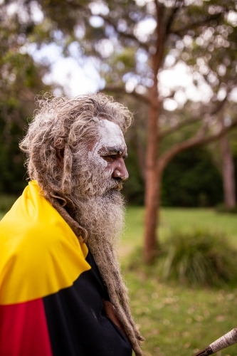 Aboriginal man wearing the Aboriginal flag around his shoulders