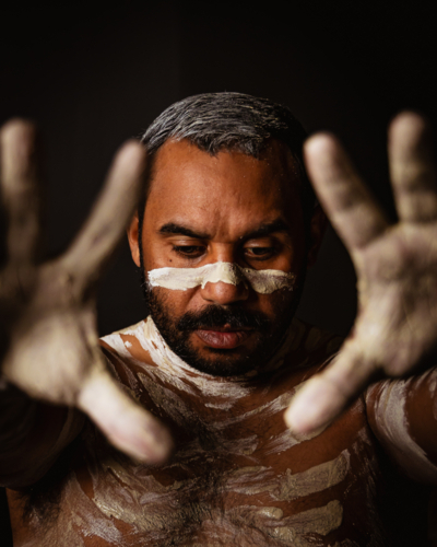 Aboriginal man with body paint extending his palms in front - Australian Stock Image