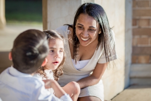 Aboriginal mother leaning forward laughing at twin children