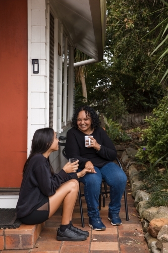 Aboriginal parent sitting together with teen on back porch - Australian Stock Image