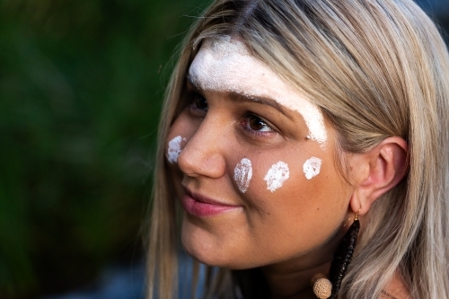 Aboriginal woman looking up in Australian bushland in traditional paint - Australian Stock Image