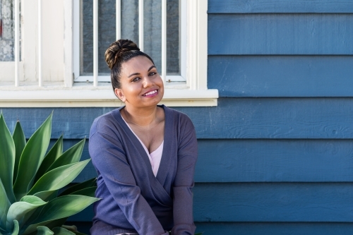 aboriginal woman sitting outside weatherboard house - Australian Stock Image
