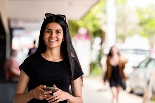 aboriginal woman walking in an urban setting, using mobile phone - Australian Stock Image