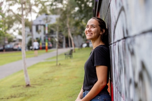 Aboriginal woman wearing a black tshirt smiling and looking out - Australian Stock Image