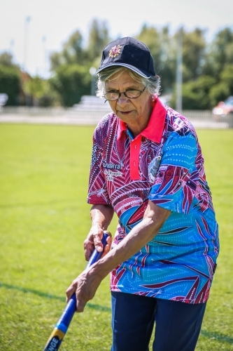 Aboriginal woman wearing hat and glasses holding hockey stick - Australian Stock Image