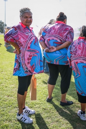 Aboriginal woman with hand on hip standing behind team - Australian Stock Image