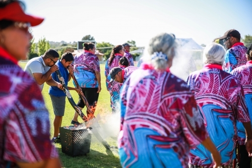 Aboriginals playing didgeridoos during smoking ceremony - Australian Stock Image