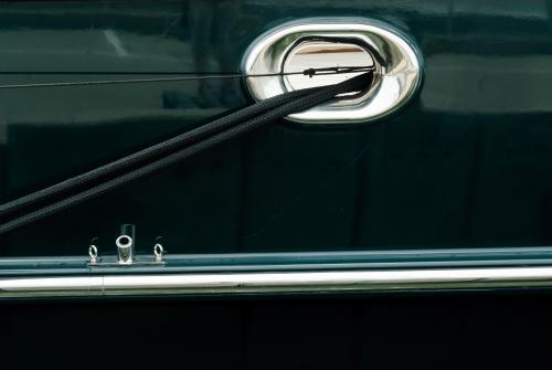Abstract - Close up of side of yacht with mooring rope and metal parts. - Australian Stock Image