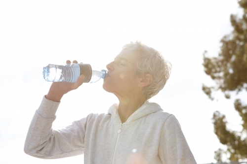 Active senior lady drinking from water bottle - Australian Stock Image