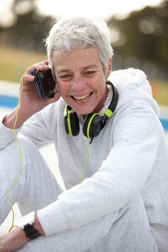 Active senior lady listening to music with headphones - Australian Stock Image