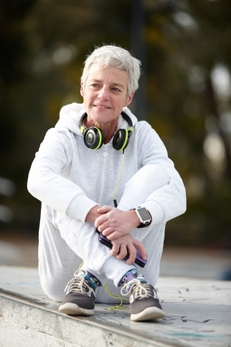 Active senior lady listening to music with headphones - Australian Stock Image