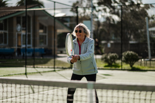 Active senior woman enjoys playing tennis at a local court. - Australian Stock Image