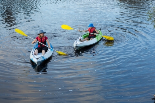 Adult and child paddling kayaks - Australian Stock Image
