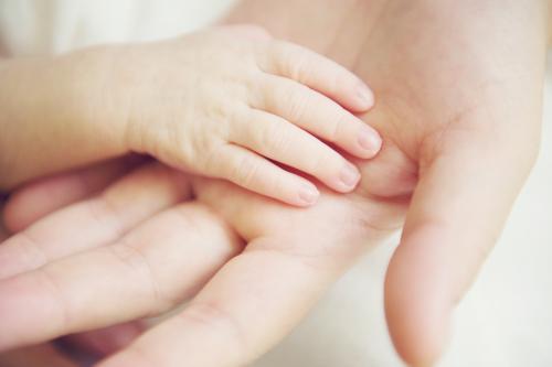 Adult hand with baby hand - Australian Stock Image