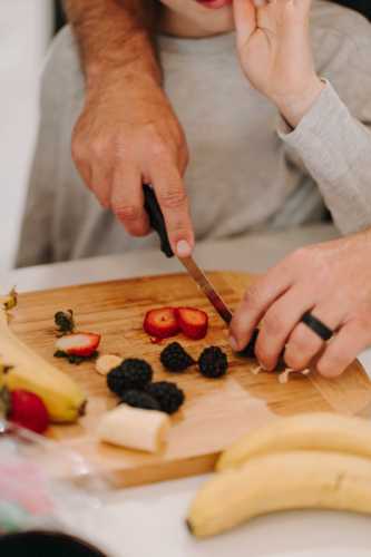 Adult male hand cutting fruit on chopping board - Australian Stock Image