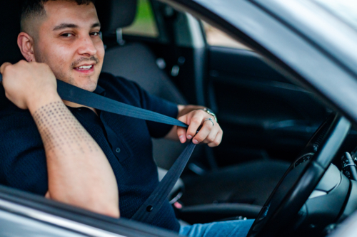 Adult man adjusts his seatbelt while parked in a park, ready for adventure - Australian Stock Image