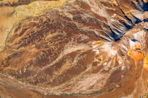 Aerial abstract of rugged desert terrain showing rich red and ochre erosion patterns - Australian Stock Image