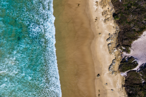 Aerial downward view of Sand Dune Beach at Brooms Head, showcasing the sandy shoreline and ocean - Australian Stock Image