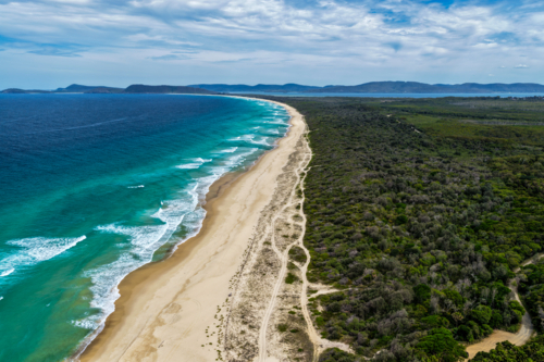Aerial drone view of Seven Mile Beach in Forster showcasing a long stretch of sandy shoreline. - Australian Stock Image