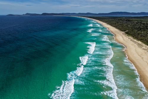 Aerial drone view of Seven Mile Beach in Forster showcasing a long stretch of sandy shoreline. - Australian Stock Image