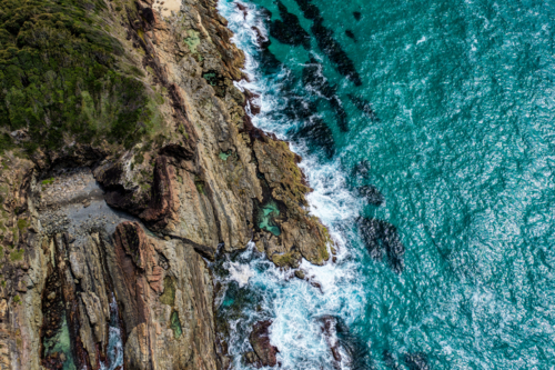 Aerial drone view over McBrides rockpool showing the natural rock formation along a rugged coastline - Australian Stock Image