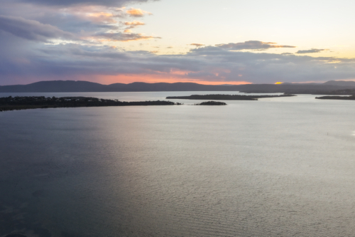 Aerial drone view over Pipers Bay in Forster, New South Wales, Australia with cloudy sky. - Australian Stock Image