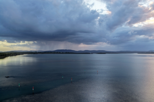 Aerial drone view over Pipers Bay in Forster, NSW, Australia with the sun setting behind the clouds - Australian Stock Image