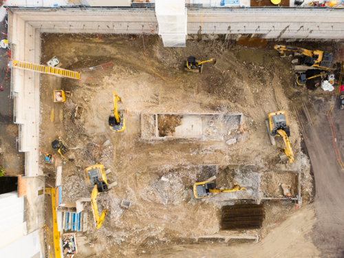 Aerial image above an excavated construction site with several machines in excavated pit - Australian Stock Image