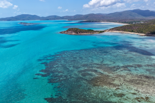 Aerial image of Hydeaway Bay, capturing its brilliant turquoise water, rocky headlands - Australian Stock Image