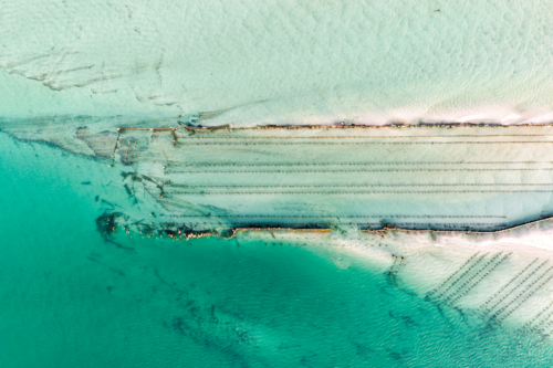 Aerial image showcasing the bright turquoise waters of Wallis Lake at low tide with patterns in sand - Australian Stock Image