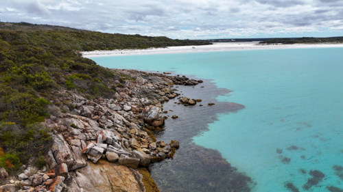 Aerial looking back at aesthetic beach with crystal water and white sand - Australian Stock Image