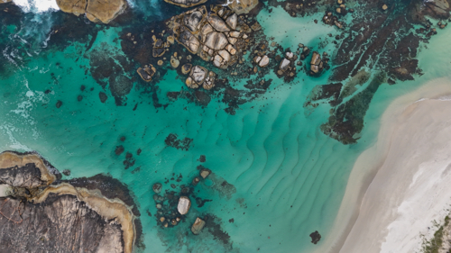 Aerial of beach with aqua water and large rocks - Australian Stock Image