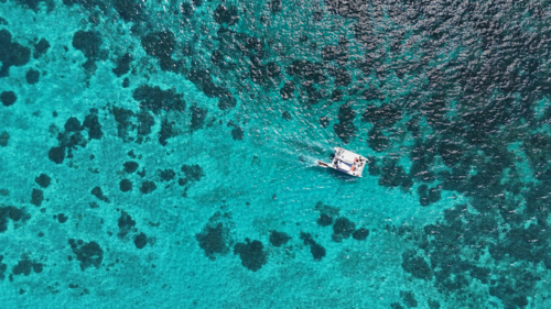 Aerial of boat driving across the reef - Australian Stock Image