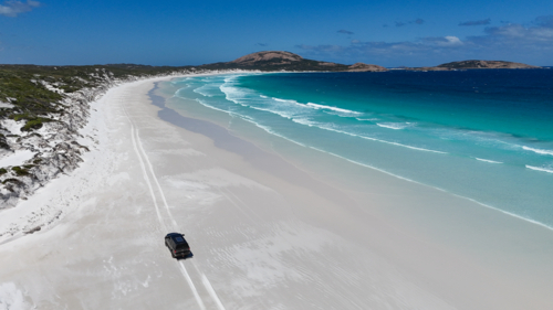 Aerial of car driving along beach - Australian Stock Image