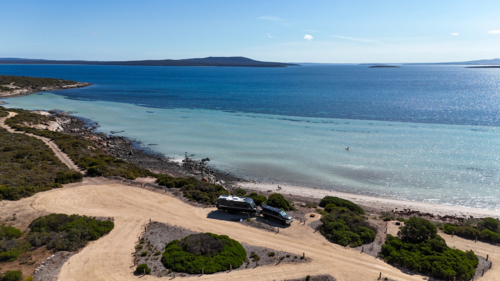 Aerial of caravan set up at campsite by a remote beach - Australian Stock Image