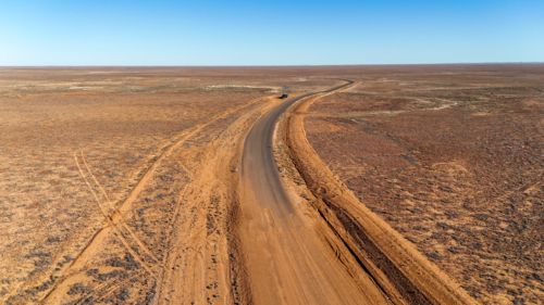Aerial of dirt road meeting the tar in the outback - sealed to unsealed road - Australian Stock Image