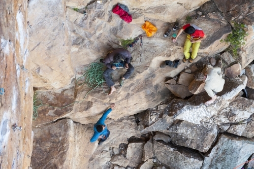 Aerial of four male rock climbers at the bottom of a crag