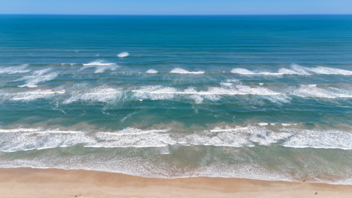 Aerial of multiple sets of waves on a remote beach - Australian Stock Image