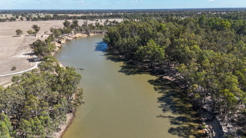 Aerial of Murray River bending through trees and rural land in dry season - Australian Stock Image