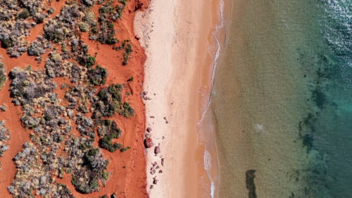 Aerial of red cliffs meeting beach - Australian Stock Image