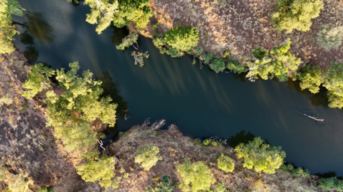 Aerial of river surrounded by grass land - Australian Stock Image