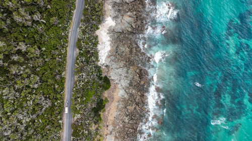 Aerial of straight road parallel to ocean - Australian Stock Image