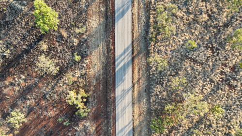 Aerial of straight road surrounded by remote grassland - Australian Stock Image
